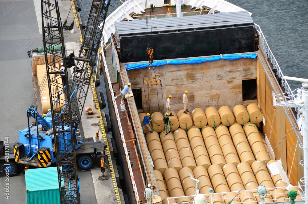Paper rolls being loaded into vessel cargo hold at port