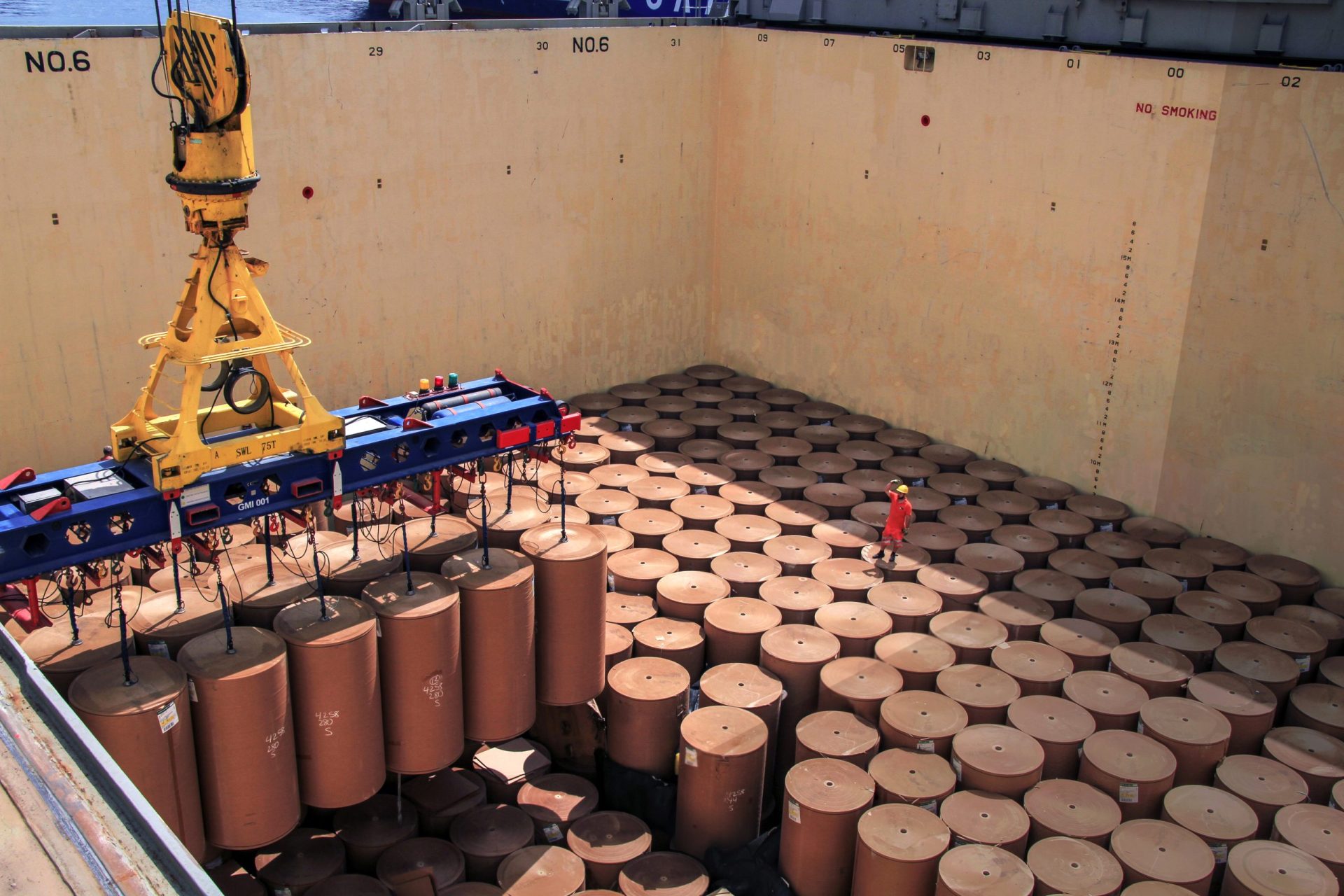 Kraft paper rolls being loaded into vessel hold by crane — G2Ocean
