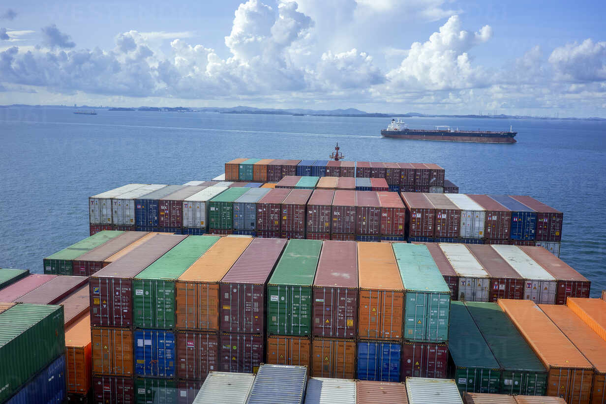 Container ship sailing at sea with colorful containers under blue sky