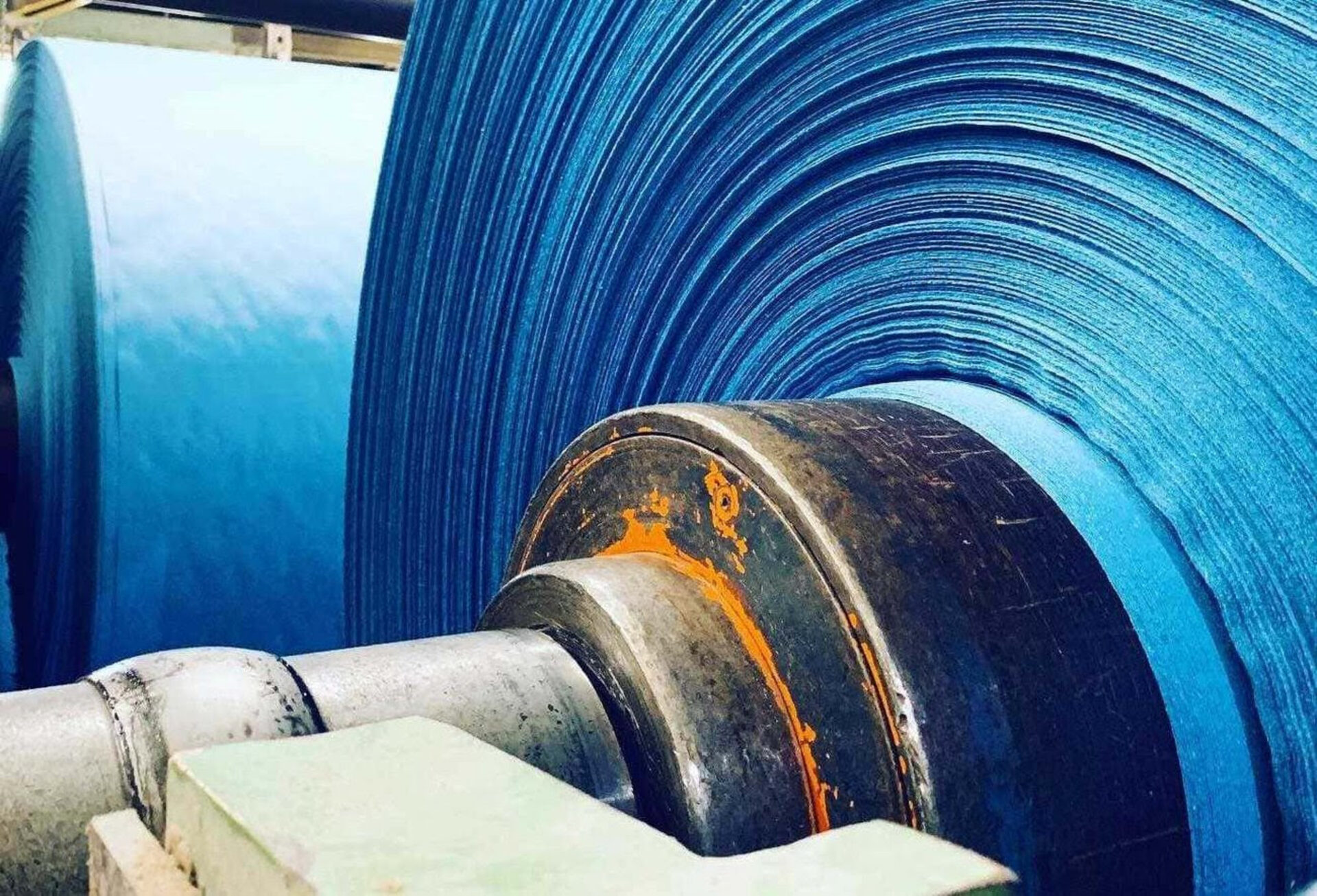 Industrial blue paper reel on winding machine with orange metal details