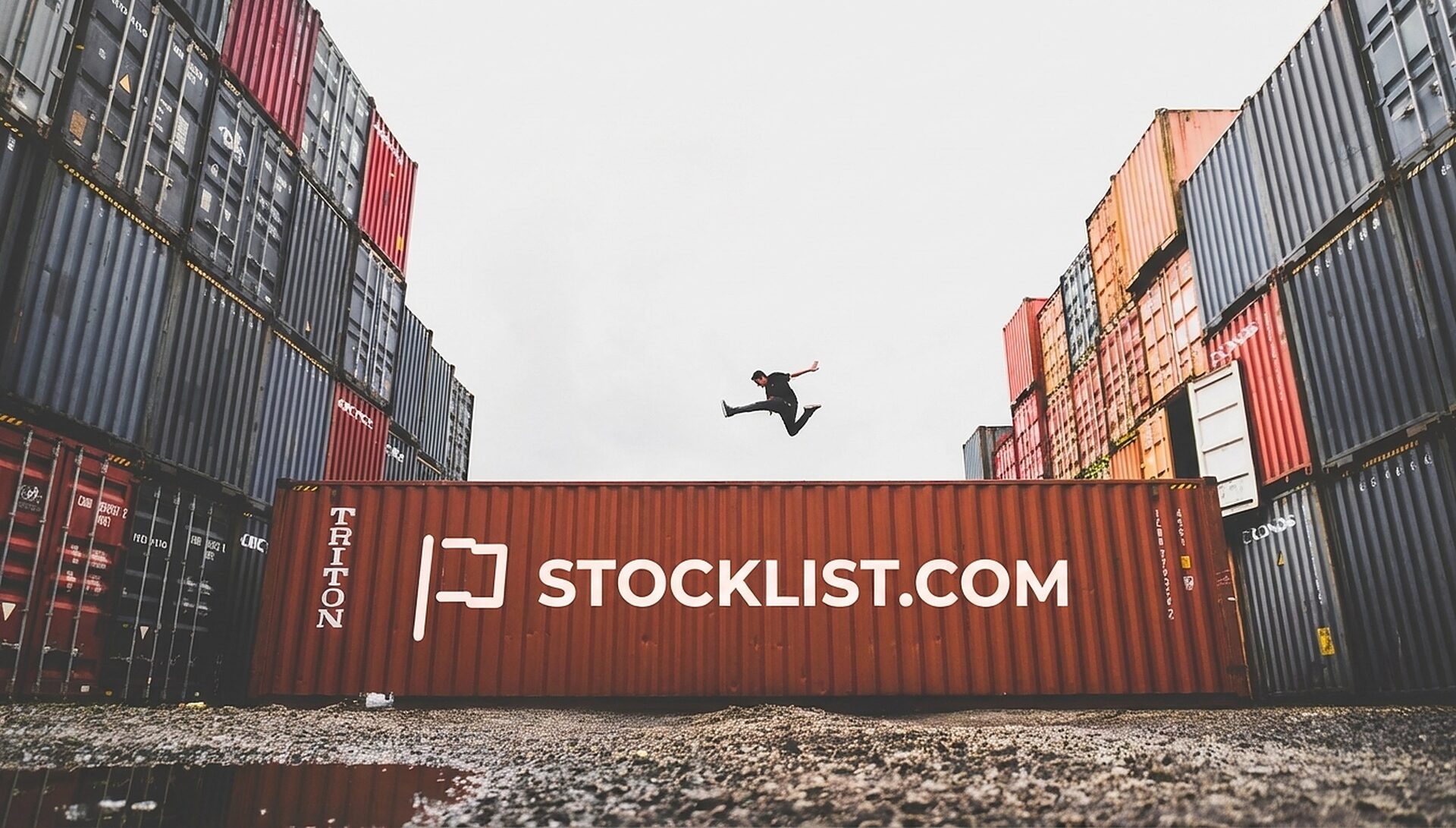 Person jumping above a branded StockList.com shipping container in a colourful container yard