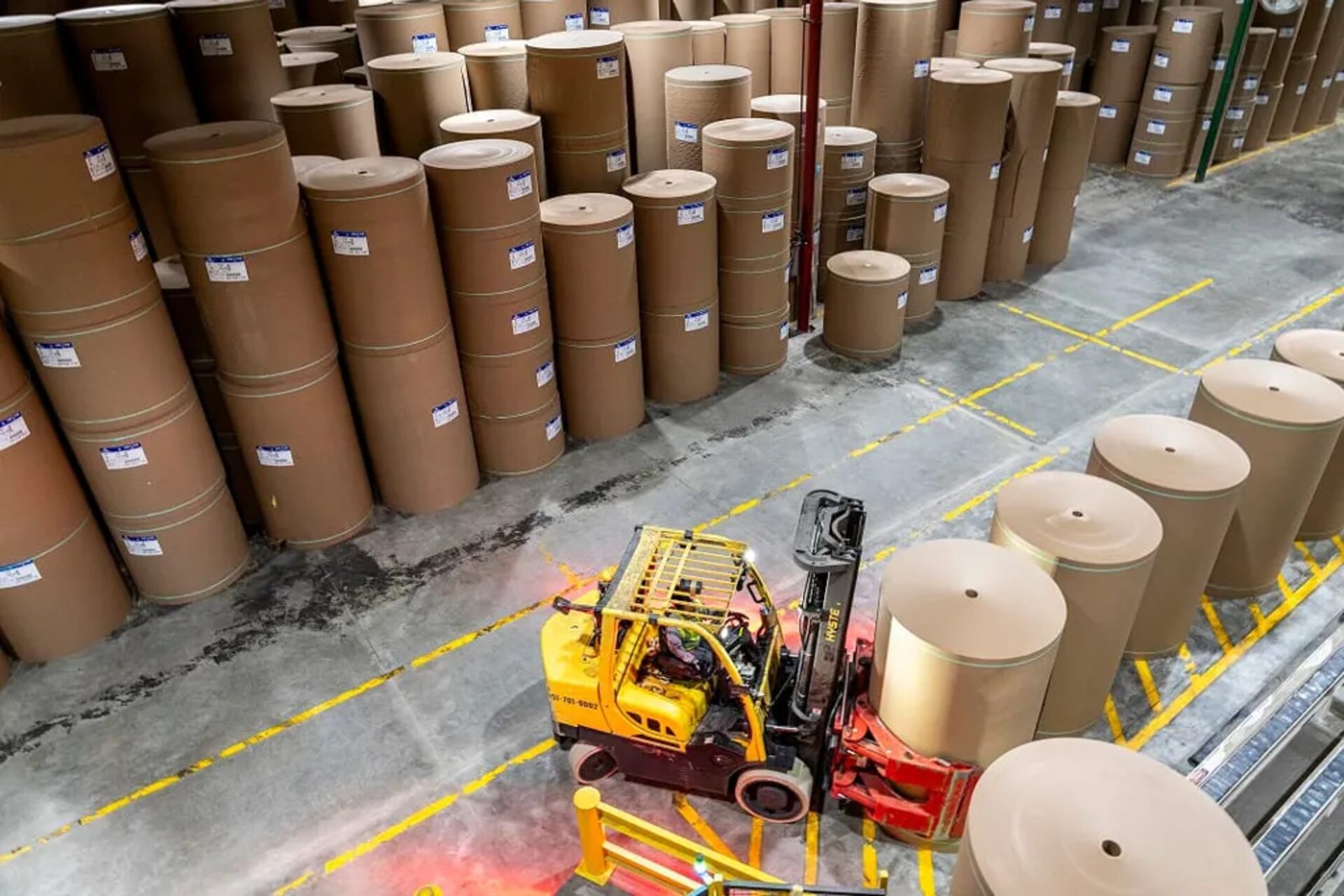 Aerial view of warehouse with kraft paper rolls and yellow forklift